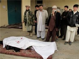 Hombres afganos observan los cuerpos de las personas muertas en Kunduz. AP  /