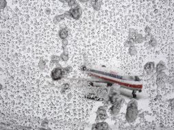 Un avión se observa a través de una ventana cubierta de hielo en el aeropuerto. AP  /