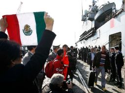 Una mujer sostiene una bandera mexicana a la llegada de evacuados de Libia al puerto de Catania. AFP  /
