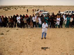 Libios rezan frente a un rifle de asalto AK-47 antes de disponerse a tomar la ciudad de Ras Lanuf. AFP  /