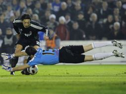 El alemán Mesut Özil (izq.), del Madrid, quien dio los pases para los primeros dos goles, es interceptado por el arquero Rodríguez. AP  /