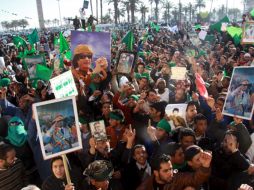 Simpatizantes de Gadafi portan posters con su retrato y ondean banderas verdes en una concentración en apoyo al régimen. EFE  /