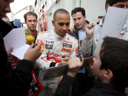 El piloto británico Lewis Hamilton firma autógrafos durante un descanso de la segunda jornada de entrenamiento de Fórmula Uno. EFE  /