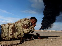 Un rebelde se cubre de los disparos de las fuerzas leales a Muamar Gadhafi, en Ras Lanuf. AFP  /