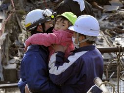 Dos socorristas rescatan a una menor abandonada en un edificio de Kesennuma, en Miyagi. AP  /