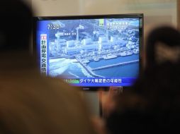 Varias personas ven las noticias informan sobre la situación en la central nuclear de Fukushima. EFE  /