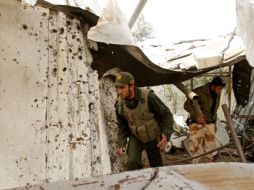 Policías palestinos del grupo Hamas inspeccionan un puesto destruido por la Armada israelí. AFP  /
