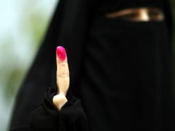 Una mujer vestida con el traje tradicional muestra su dedo tras emitir su voto en El Cairo. NTX  /