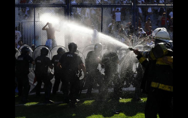 Elementos de seguridad lanzan agua a los aficionados que trataban de ingresar a la cancha. REUTERS  /