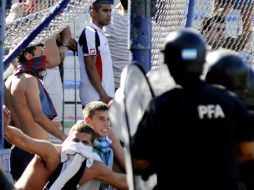 Elementos de seguridad tratan de impedir la entrada de los aficionados a la cancha del estadio de Vélez. EFE  /
