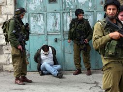 Soldados israelíes arrestan a un palestino en el pueblo de Beit Omar. AFP  /