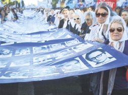 Mujeres de Plaza de Mayo sostienen la bandera argentina con cientos de rostros de las víctimas del régimen de Jorge Rafael Videla. EFE  /