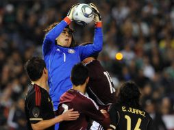 Guillermo Ochoa (c) se queda con un balón durante el juego ante Venezuela, el arquero ha sido críticado por la prensa por su falla. AFP  /