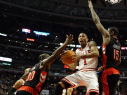 El jugador Derrick Rose (centro), de los Toros de Chicago, intenta encestar ante la marca de Reggie Evans (i) y Amir Johnson (d). EFE  /