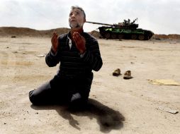Un insurgente reza cerca de un tanque destruido por los bombardeos de la OTAN, en la ciudad de Ajdabiya. EFE  /