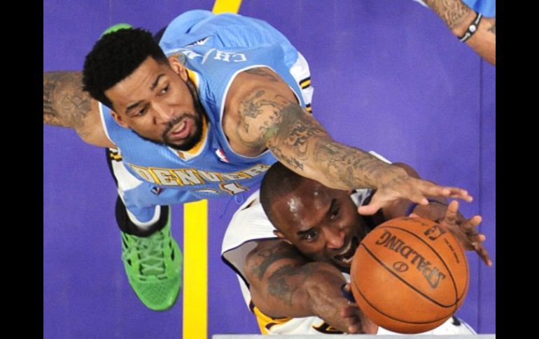 Kobe Bryant va en busca del balón, luchando contra el jugador de los Nuggets, Wilson Chandler. AP  /