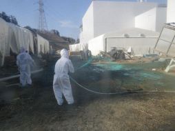 Trabajadores rocían resina adhesiva sintética sobre un patio de la planta nuclear de Fukushima. REUTERS  /