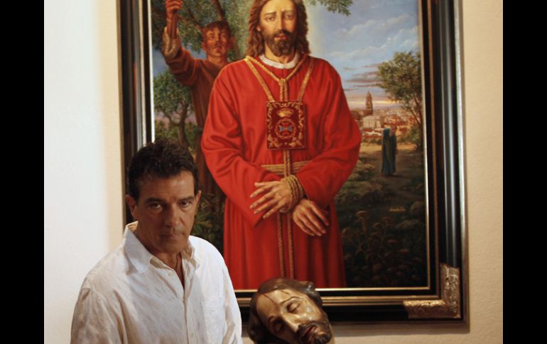Posa para los fotógrafos cerca de una pintura y la escultura de Cristo que llega para una conferencia de prensa en Málaga. REUTERS  /