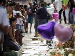 Una mujer llora ante globos, flores y notas de pésame colocados delante de la escuela de Tasso da Silveira. REUTERS  /