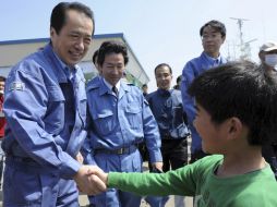 El primer ministro japonés Naoto Kan saluda a un niño, durante su visita a la zona devastada por el tsunami de marzo. AP  /