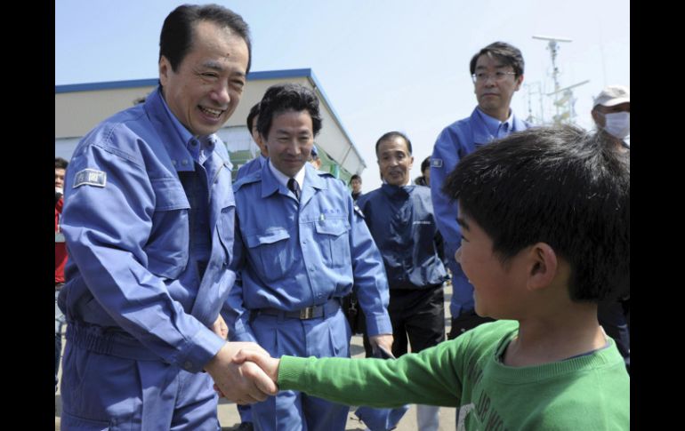 El primer ministro japonés Naoto Kan saluda a un niño, durante su visita a la zona devastada por el tsunami de marzo. AP  /