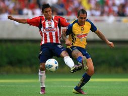 Alberto Medina, del Guadalajara, lucha por el balón contra Daniel Montenegro, en el Clásico Nacional. AFP  /