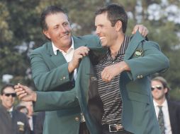 El campeón de 2010 Phil Mickelson (izq.) le coloca el saco verde de campeón a Charl Schwartzel. REUTERS  /