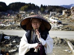 Una mujer reza en medio de una calle que quedó en ruinas luego del terremoto y el tsunami del pasado 11 de marzo, en Japón. AP  /