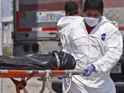 Empleados del servicio forense de la entidad transportan uno de los cuerpos hallados. AP  /