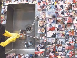 Un voluntario limpia fotos de distintas familias que fueron mojadas por el agua del tsunami. REUTERS  /