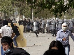 Manifestantes iraquíes corren a esconderse de la policía antidisturbios. AFP  /