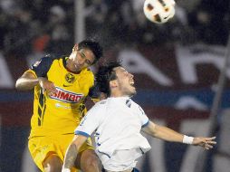Juan Carlos Valenzuela, del América, disputa la pelota con Jonathan Charquero, de Nacional. AP  /
