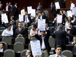 Legisladores panistas muestran carteles en los que cuestionan la pasividad de los diputados del PRI. EL UNIVERSAL  /