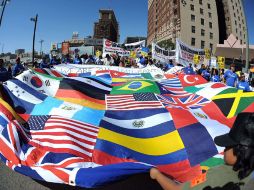 Decenas de inmigrantes ondean una mega bandera hecha con los símbolos de varios países, en Los Ángeles. AFP  /