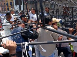 Organizadores y policías capitalinos auxilian a una persona que quedó bajo la estructura de un templete. NTX  /