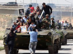 Vecinos abordan tanques del Ejército sirio como muestra de adhesión a las fuerzas leales al Gobierno. AFP  /