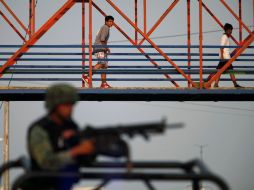 Unos niños cruzan un puente sobre el sitio donde cinco hombres que iban en una camioneta fueron asesinados hoy. REUTERS  /