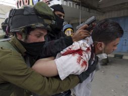 Policías israelíes detienen a un palestino durante los enfrentamientos registrados en el campo de refugiados cisjordano de Kalandia.EFE  /