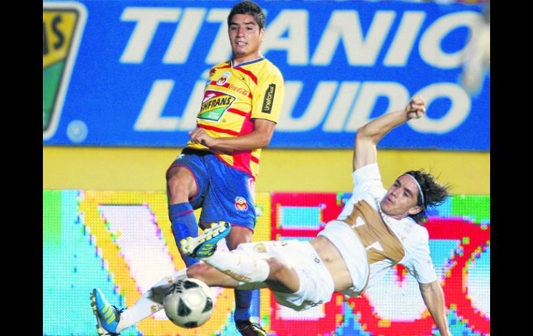 Enrique Pérez, de Morelia, y Efraín Velarde, de Pumas, disputan un balón, anoche en el Morelos. AP  /