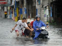 Una familia intenta trasladarse por las calles de Manila, a pesar de las inundaciones. AFP  /