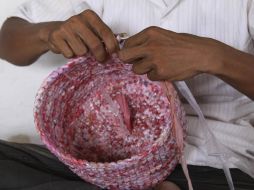 Una mujer hace un canasto con bolsas de plástico recicladas. EFE  /