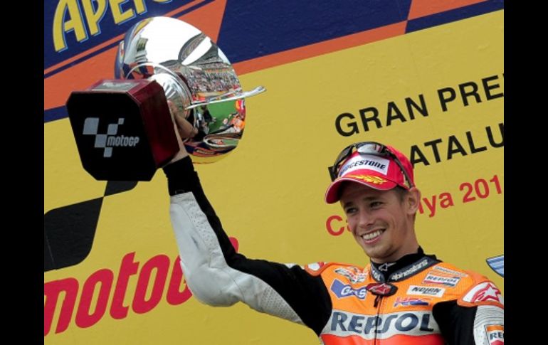 El australiano Casey Stoner sube a lo más alto del podio con el trofeo en mano. AFP  /