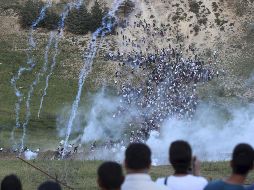 Palestinos se ponen a cubierto de los disparos de soldados israelíes. EFE  /