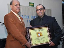 El fotógrafo Alfredo García recibe el galardón de manos de Miguel Rivera, presidente de la Asociación Nacional de Periodistas. ESPECIAL  /