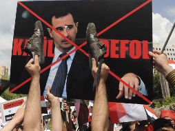 Manifestantes ofenden una pancarta del presidente sirio, Bachar al Asad. EFE  /
