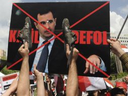 Manifestantes levantan una pancarta del presidente sirio durante una protesta ante la embajada siria en Ankara, Turquía. EFE  /