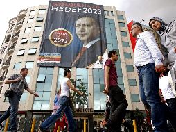 Ciudadanos turcos caminan frente a un cartel electoral del primer ministro turco, Recep Tayyip Erdogan. EFE  /