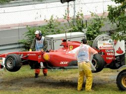 Empleados retiran el auto del piloto español Fernando Alonso del equipo Ferrari tras un accidente. EFE  /