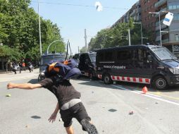 Un joven manifestante del movimiento 15-M lanza un objeto contra las furgonetas de la Brigada Móvil de la policía de Cataluña. EFE  /