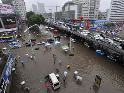 Personas y coches pasan por las calles inundadas en Wuhan en la provincia central china de Hubei. AP  /